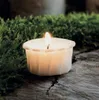 A lit tea light candle sits on a wooden surface surrounded by moss. Podgląd zdjęcia produktu