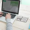 A person's hands are typing on a laptop, with a separate numeric keypad to the right, on a wooden desk. Náhled obrázku produktu