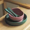 A pink bowl and green plate with two green spoons on a wooden surface. Náhľad obrázku produktu