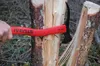 A hand holding a red STUBAI axe, splitting a log in a forest setting. Produktbild-Vorschau