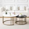 Two round coffee tables, one white with marble effect and one black, are placed on a carpet in front of a sofa. Produktbild-Vorschau