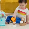 A baby is playing with a toy coffee maker and accessories on a rug. Náhľad obrázku produktu