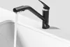 A black kitchen faucet with water running into a white sink. Produktbild-Vorschau