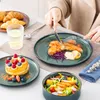 A person is eating a meal consisting of salmon, salad, and dessert, with croissants and a drink on the side. Náhled obrázku produktu