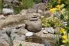 A close-up view of a decorative garden pond with a stack of stones in the center. Produktbild-Vorschau