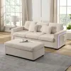 A beige sofa and ottoman set in a well-lit room with large windows. Anteprima dell’immagine prodotto