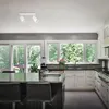 A modern kitchen with white cabinets, a dark countertop, and large windows overlooking a wooded area. A track light fixture is visible on the ceiling. Podgląd zdjęcia produktu