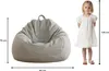 A child is standing next to a beanbag chair, with dimensions indicated by lines and text. Produktbild-Vorschau