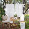 An outdoor garden setting with two chairs and a small table, decorated with white lace curtains. Náhľad obrázku produktu
