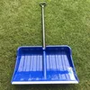 A blue snow shovel lying on green grass. Voir les images du produit