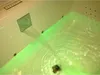 A close-up view of a bathtub with water flowing from a chrome spout, illuminated by green LED lights. Anteprima dell’immagine prodotto