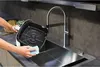 A person is cleaning the basket of an air fryer in a kitchen sink. Voir les images du produit