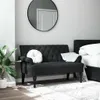 A black tufted bench with a round white pillow and a white throw blanket is placed in a bedroom setting next to a bed. A large round mirror hangs on the wall above the bench, and a potted plant is visible to the left. Voir les images du produit