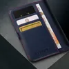 A close-up view of a blue leather wallet case for an iPhone, showing credit cards and cash inserted. Produktbild-Vorschau