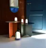 Three LED lanterns are displayed on two side tables in a room with a blue door and brown wall. Produktbild-Vorschau