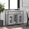 A sideboard with glass doors and shelves is placed in a room with a window and a plant. Produktbild-Vorschau