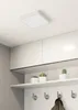 A white square LED ceiling light mounted on a white ceiling above white cabinets and shelves with potted plants and hooks. Anteprima dell’immagine prodotto