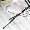 A close-up view of a folded pink garment on a black metal ironing board. Voir les images du produit