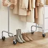 A clothing rack with coats and accessories, and boots on the floor. Produktbild-Vorschau