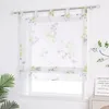 A sheer Roman blind with a floral pattern hangs in a window. Produktbild-Vorschau
