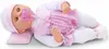 A baby doll lying on its side on a pink pillow. Podgląd zdjęcia produktu