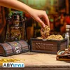 A hand reaching for a cookie from a treasure chest-shaped cookie jar, with a lantern and other items in the background. Anteprima dell’immagine prodotto