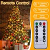 A decorated Christmas tree with gifts underneath, next to a remote control and feature callouts. Produktbild-Vorschau