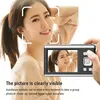 A woman is posing for a photo while holding a digital camera. Produktbild-Vorschau