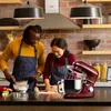 A couple is baking in a kitchen, with a stand mixer prominently displayed. Produktbild-Vorschau