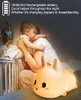 A mother holding a baby next to a crib, with a glowing bunny-shaped night light in the foreground. Produktbild-Vorschau