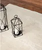 A close-up view of a cream-colored rug with two black geometric lanterns and white candles on it, with a wooden floor in the background. Produktbild-Vorschau