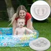A mother and baby are playing in an inflatable pool in a grassy yard. There are two inset images showing a close-up of the inflatable foot basin. Produktbild-Vorschau