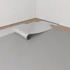 A roll of underlayment material is being unrolled onto a floor, with wood planks visible in the background. Produktbild-Vorschau