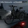 An e-bike is shown in a dark, urban setting with its headlights and taillights illuminated. Produktbild-Vorschau