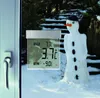 A digital window thermometer is attached to a window, showing temperature readings, with a snowman visible in the snowy background. Náhľad obrázku produktu