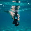 A hand holding a waterproof camera case with a digital camera inside, submerged underwater. Produktbild-Vorschau