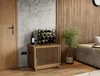 A wine rack is placed on a wooden cabinet next to a door and a plant, in a room with a textured wall and wooden paneling. Náhled obrázku produktu