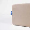A close-up of a beige fabric product with a blue tag attached to the side. Náhled obrázku produktu