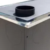 Close-up of the top corner of a black stove with a silver trim and a black pipe fitting. Produktbild-Vorschau