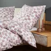 A close-up view of a bed with patterned bedding and a bedside table with candles. Produktbild-Vorschau