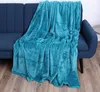 A teal-colored blanket is draped over a dark blue sofa. Náhľad obrázku produktu