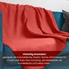 A red blanket draped over a blue sofa. Náhled obrázku produktu