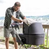 A man is adjusting a sunshade on a baby stroller outdoors with a scenic view in the background. Produktbild-Vorschau