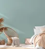 A bedroom scene with a chair and a bed, decorated with natural elements. Produktbild-Vorschau