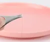 A close-up shot of tweezers holding a single hair against a pink background. Produktbild-Vorschau