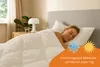 A woman sleeping peacefully under a white duvet in a bedroom. Produktbild-Vorschau