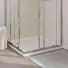 A close-up view of a shower tray and its chrome frame, with a white tiled wall in the background and a grey rug on the floor. Anteprima dell’immagine prodotto