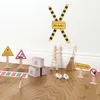 A collection of miniature construction-themed decorative items, including signs, boxes, a ladder, and a broom, arranged on a wooden floor against a white wall. Produktbild-Vorschau