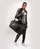 A man poses with a duffel bag, wearing a tracksuit. Voir les images du produit