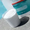 A measuring cup filled with white granular product sits next to a white bottle of pool treatment. Produktbild-Vorschau